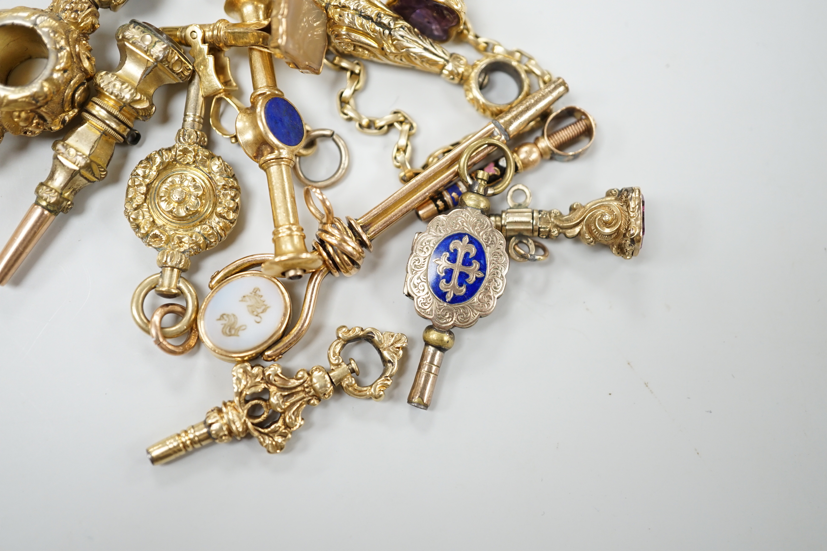 A small collection of fifteen assorted mainly 19th century yellow metal or gold plated watch keys including, one rose cut diamond set, one enamelled locket, six gem stone set, one enamelled, one surmounted with deer and